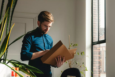 A Man Standing In An Office Holding A Box 9F1802f2ee29b7853d334ddb78ee8cf9 1600